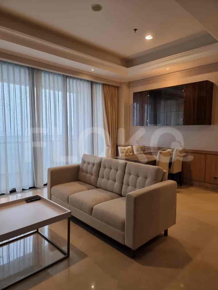 Ruang tamu dan makan yang terang dengan sofa krem, meja makan, dan jendela besar dengan tirai tipis.