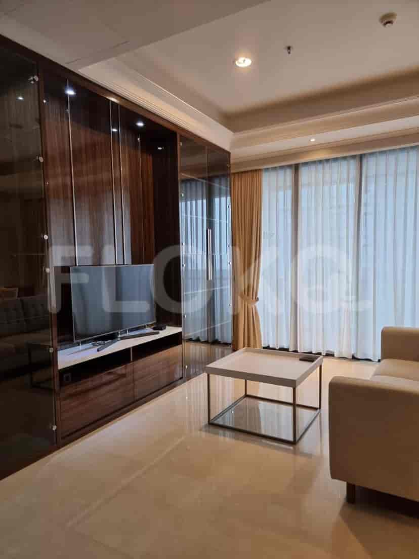 Ruang tamu modern dengan TV, sofa, dan jendela besar dengan tirai tipis.