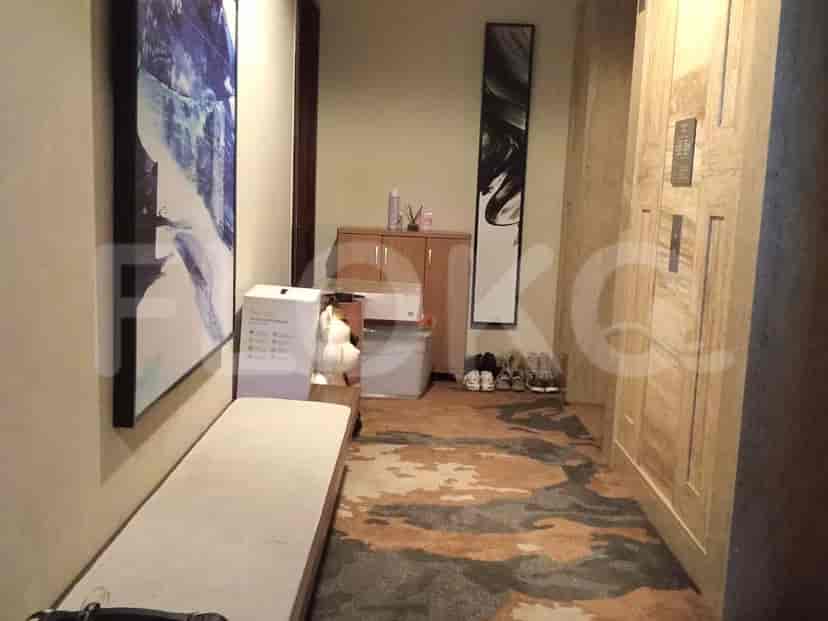 A hallway with a bench, artwork, and shoe storage.