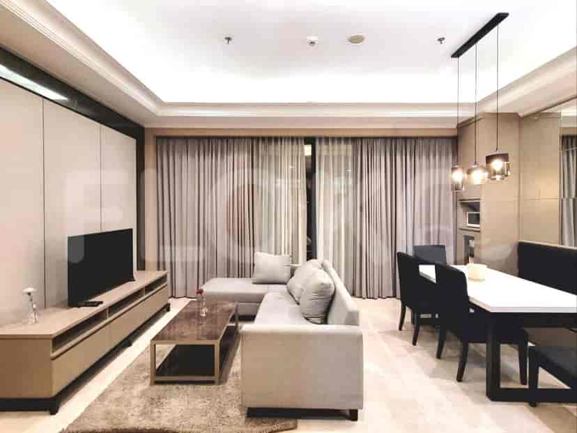 Modern living room with a grey L-shaped sofa, TV, and dining area.