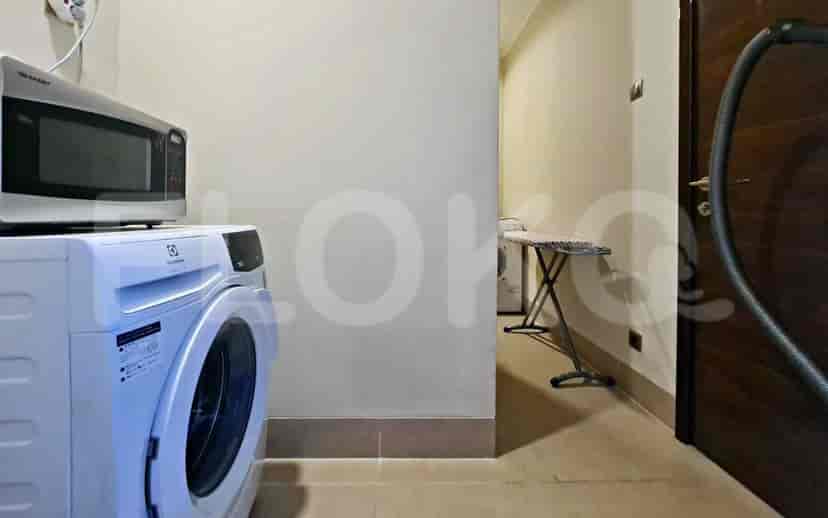Ruang cuci yang menampilkan mesin cuci, microwave, dan papan setrika.