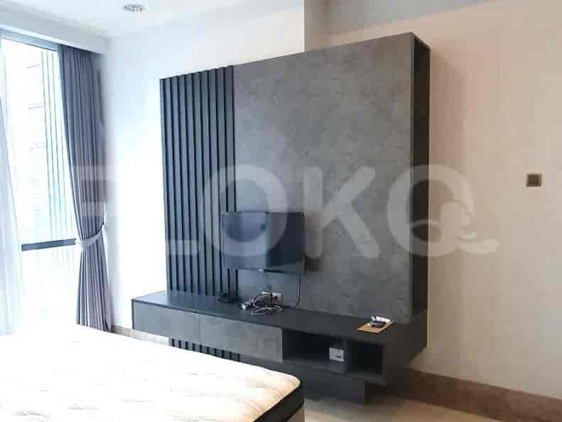 Kamar tidur dengan TV, dinding aksen abu-abu, dan tempat tidur.