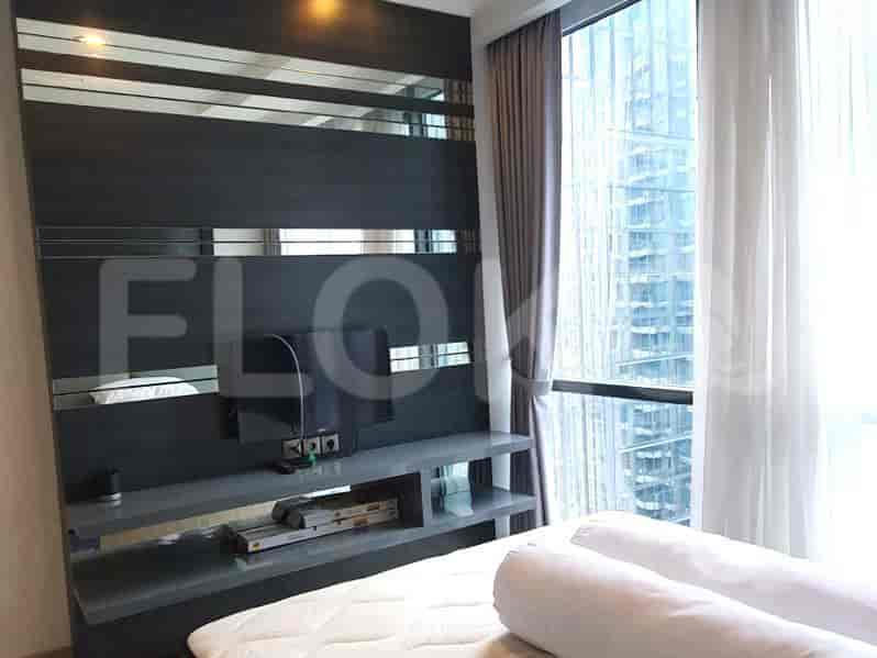 Kamar tidur dengan TV, tempat tidur, dan jendela besar.