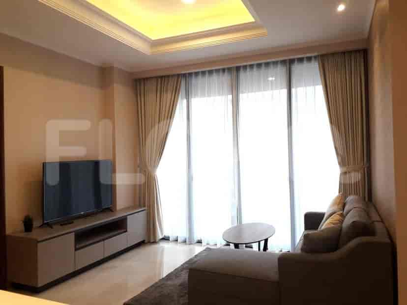 Ruang tamu dengan TV, sofa, dan jendela besar.
