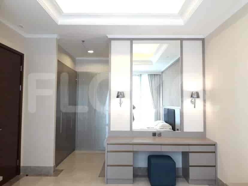 A dressing area with a large mirror, vanity, and a stool.