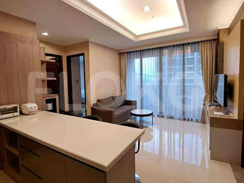 Living room with a sofa, coffee table, and large windows with curtains.