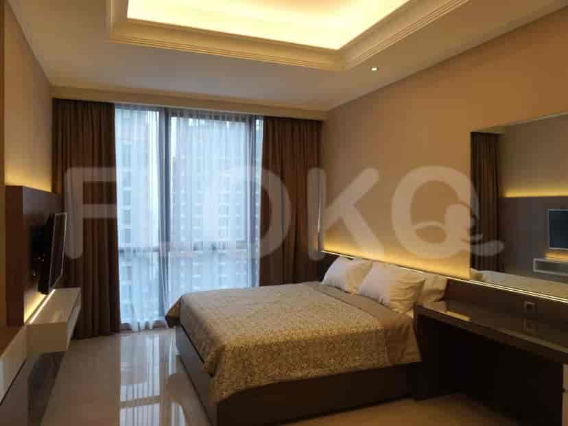 A luxurious bedroom featuring a large bed, a TV, and a window with curtains.