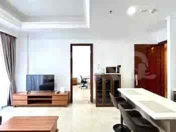 Combined living and kitchen area, featuring a kitchen bar, smart TV on a stand, and an entrance to the bedroom.