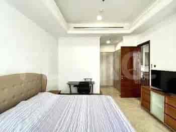 A comfortable bedroom with a bed, a desk, and a wall-mounted TV.