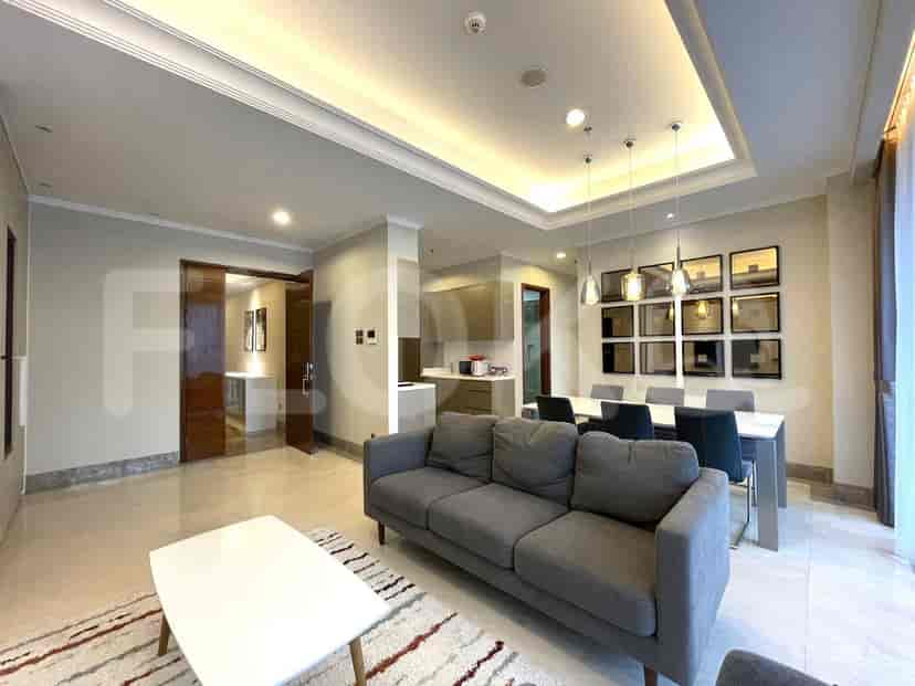 An open-plan living and dining space featuring a grey sofa, dining table, and kitchen access.