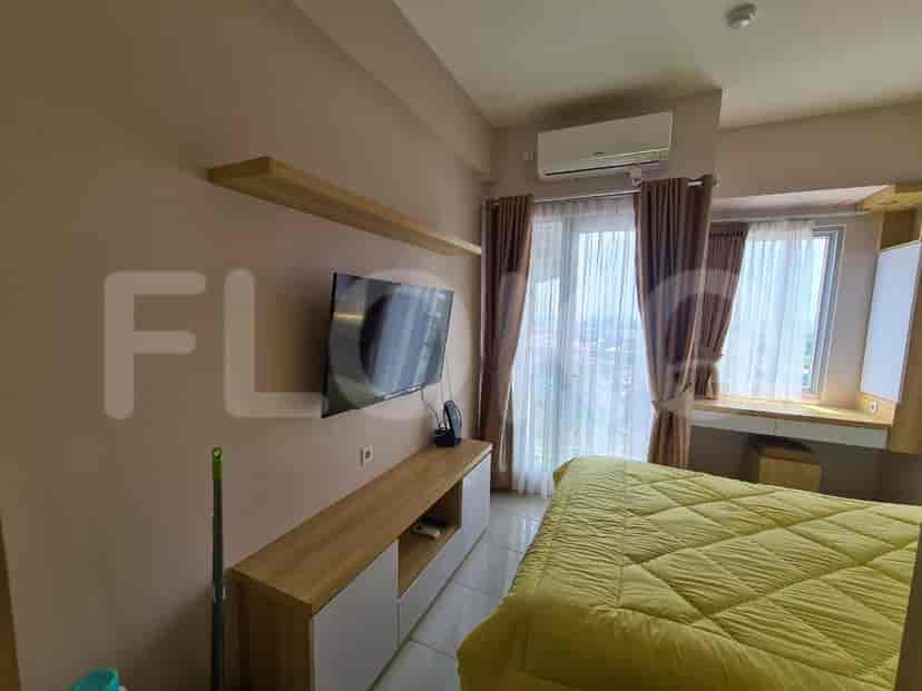 Bedroom with a TV, AC unit, and a view of the city from the window.