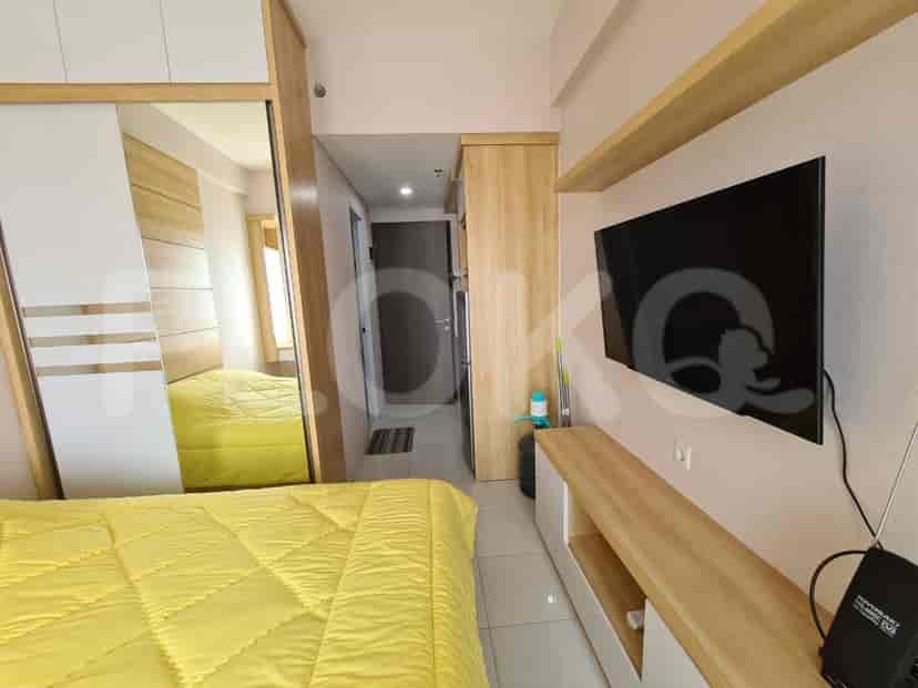 A bedroom showing a bed, TV, and a partially open door to another room.