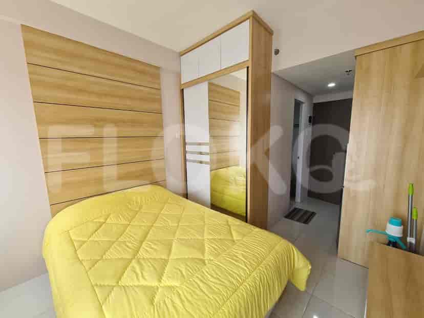 A modern bedroom with a yellow quilt on the bed, wooden paneling, and a mirrored closet.
