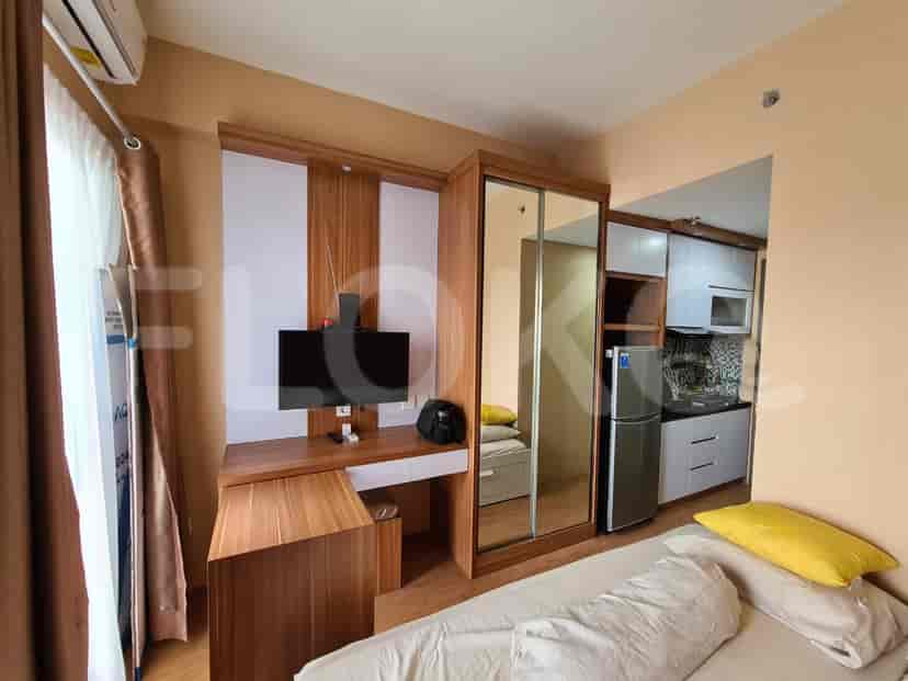 A compact living space with a desk, bed, and a kitchen area.