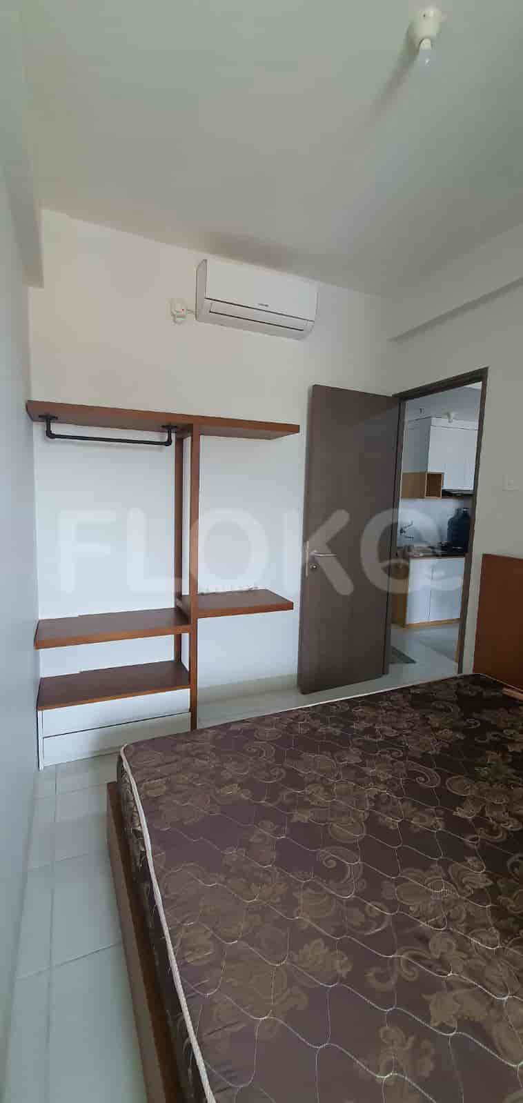 A compact bedroom featuring a bed, wardrobe, and open doorway to the kitchen.