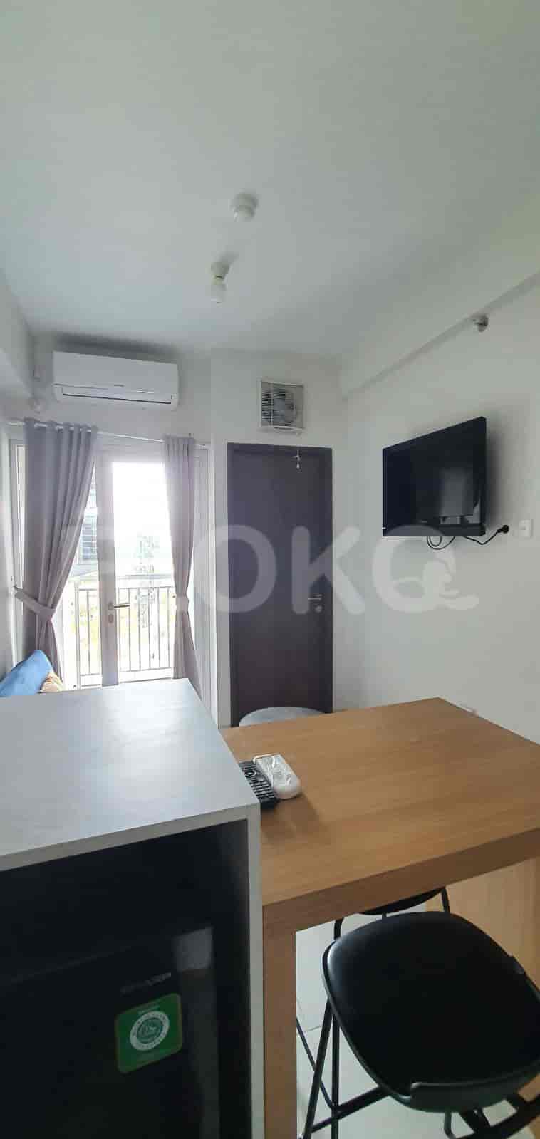Living room with a TV, dining area, and access to a balcony.