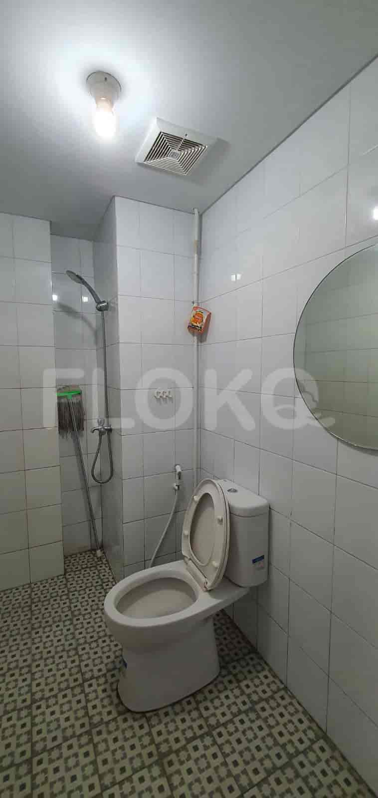 A white bathroom with a toilet, shower, and mirror.