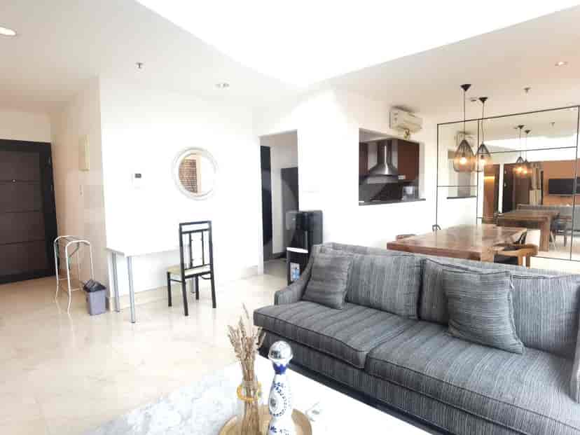 Ruang tamu dengan meja, sofa, dan tata letak terbuka, menyoroti desain modern.