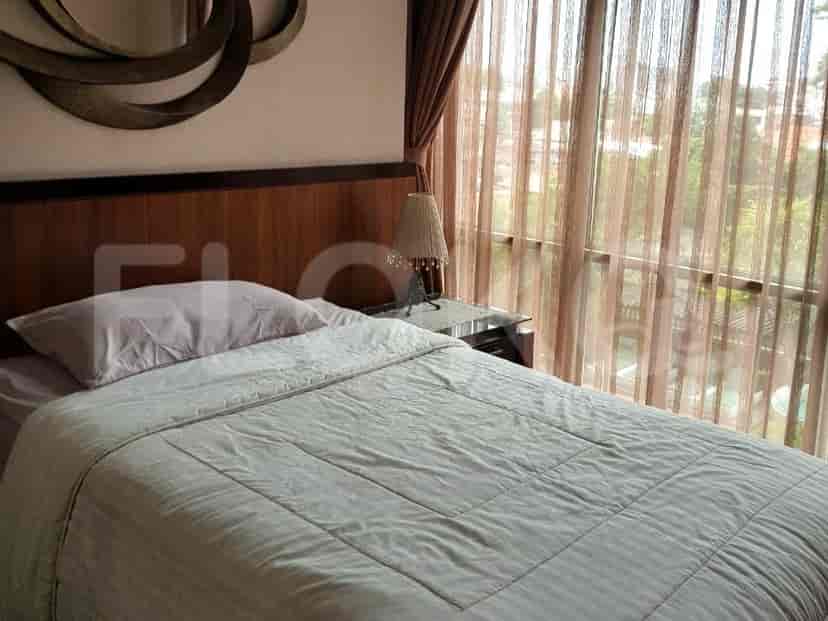A bedroom with a bed, a side table, and curtains.