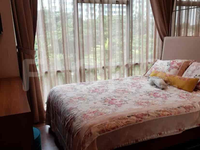 A bedroom with a bed and large windows with curtains.