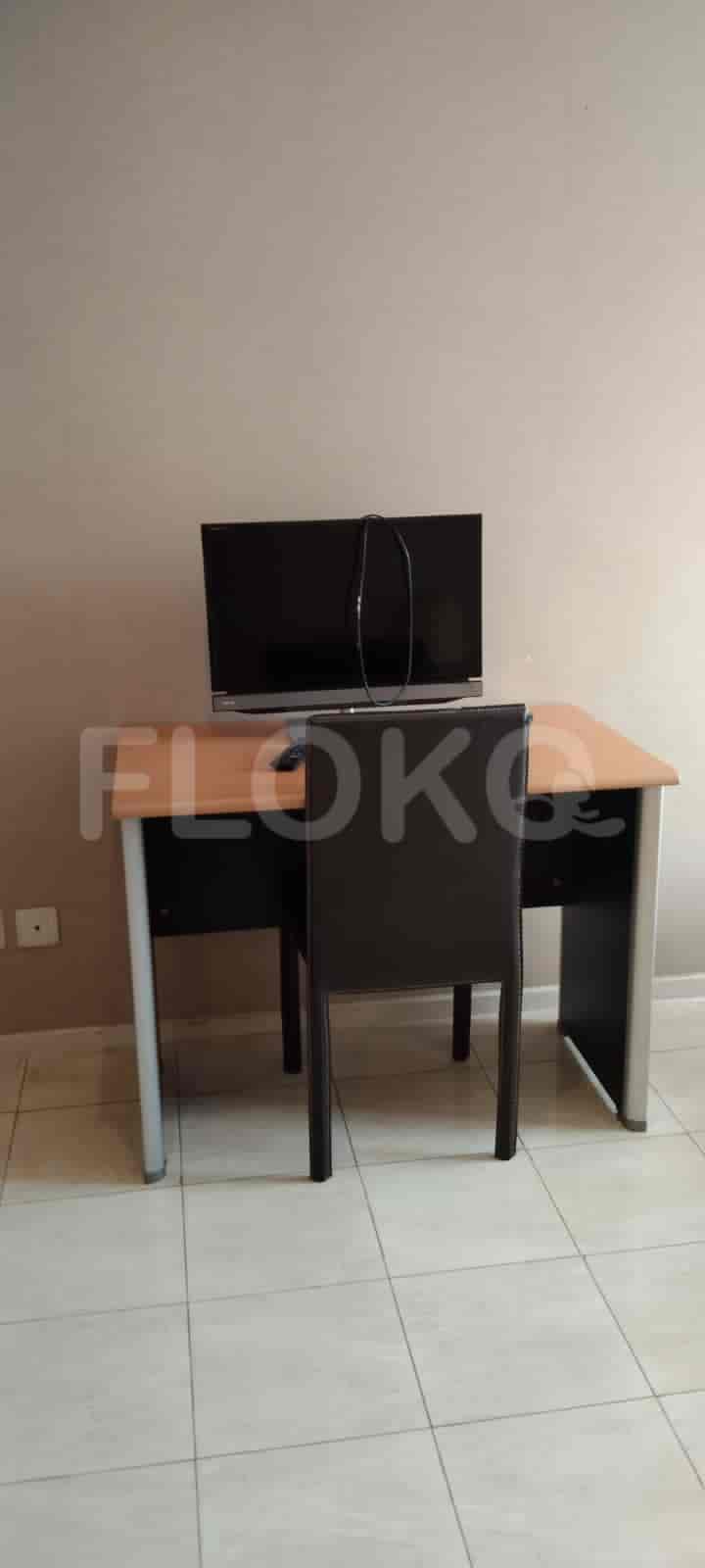 A small office area with a desk, chair, and TV.