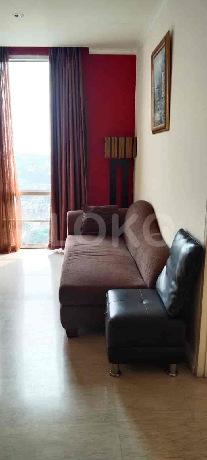 A living room featuring a brown sectional sofa and a black ottoman near a window.