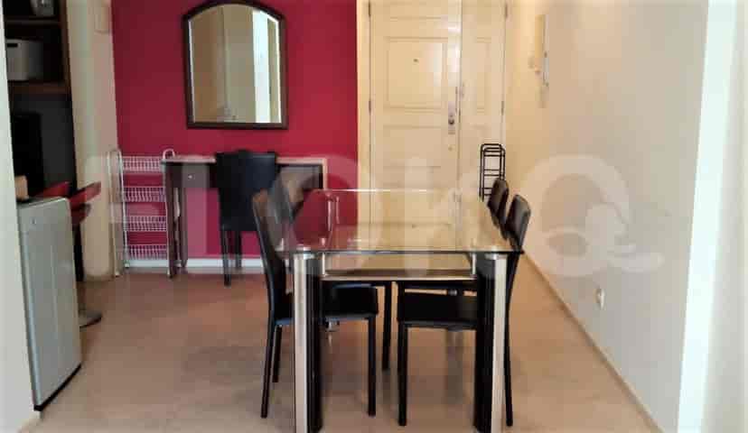 A dining area with a glass table, black chairs, and access to other rooms.