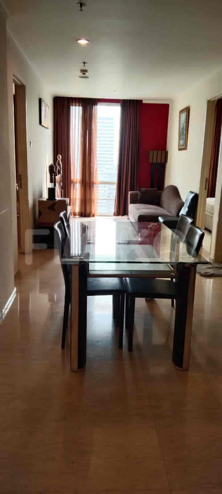 A combined dining and living area with a dining table, sofa, and access to a balcony.