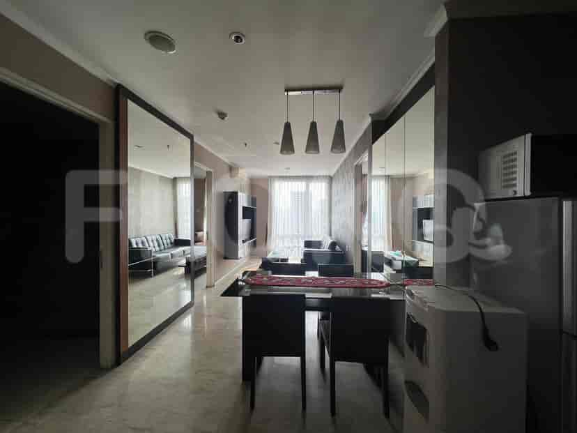 A modern living and dining area with a glass dining table, black chairs, and a view of the city through the window.