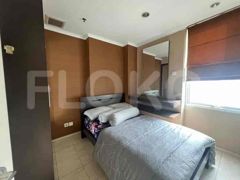 A bedroom with a bed, a mirror, and brown walls.