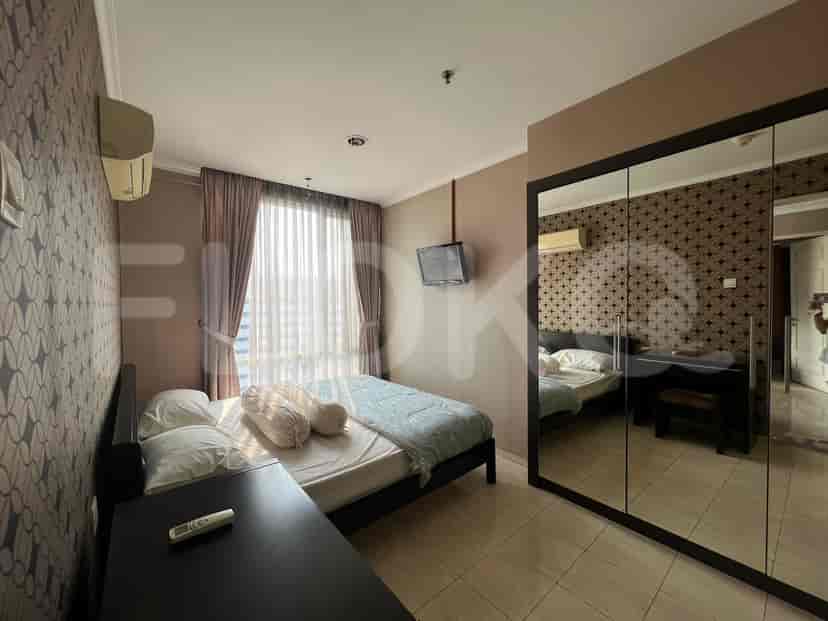 A bedroom with a bed, a TV, and a window with curtains.