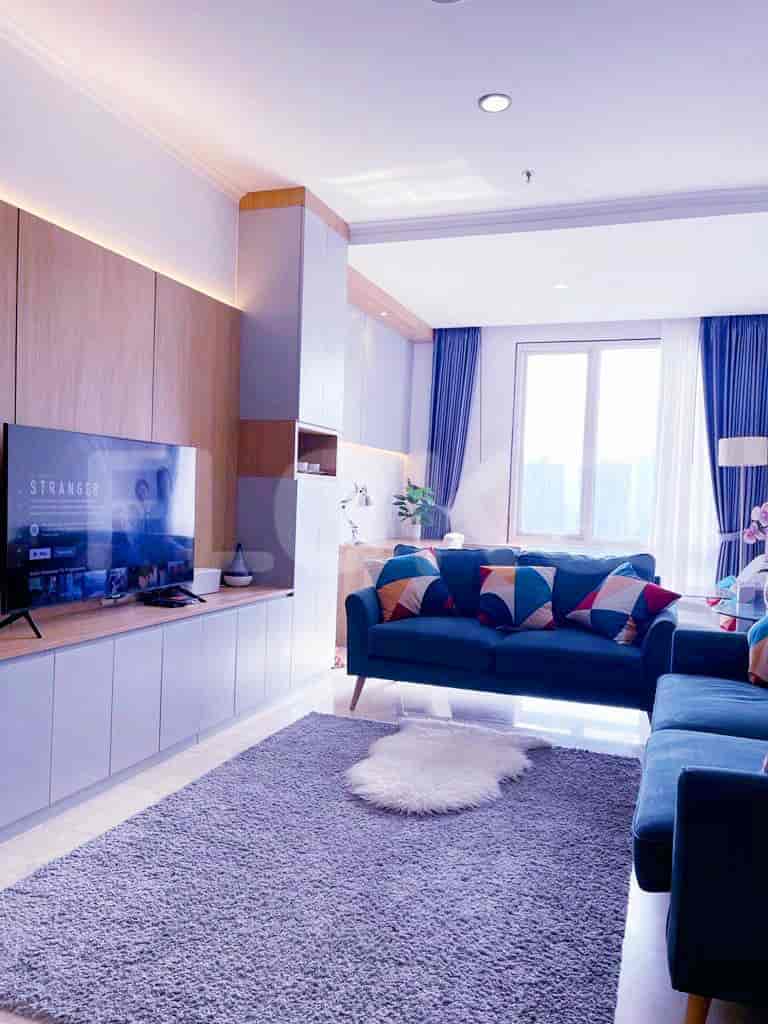 A modern living room featuring a large sofa, entertainment center, and access to the kitchen.