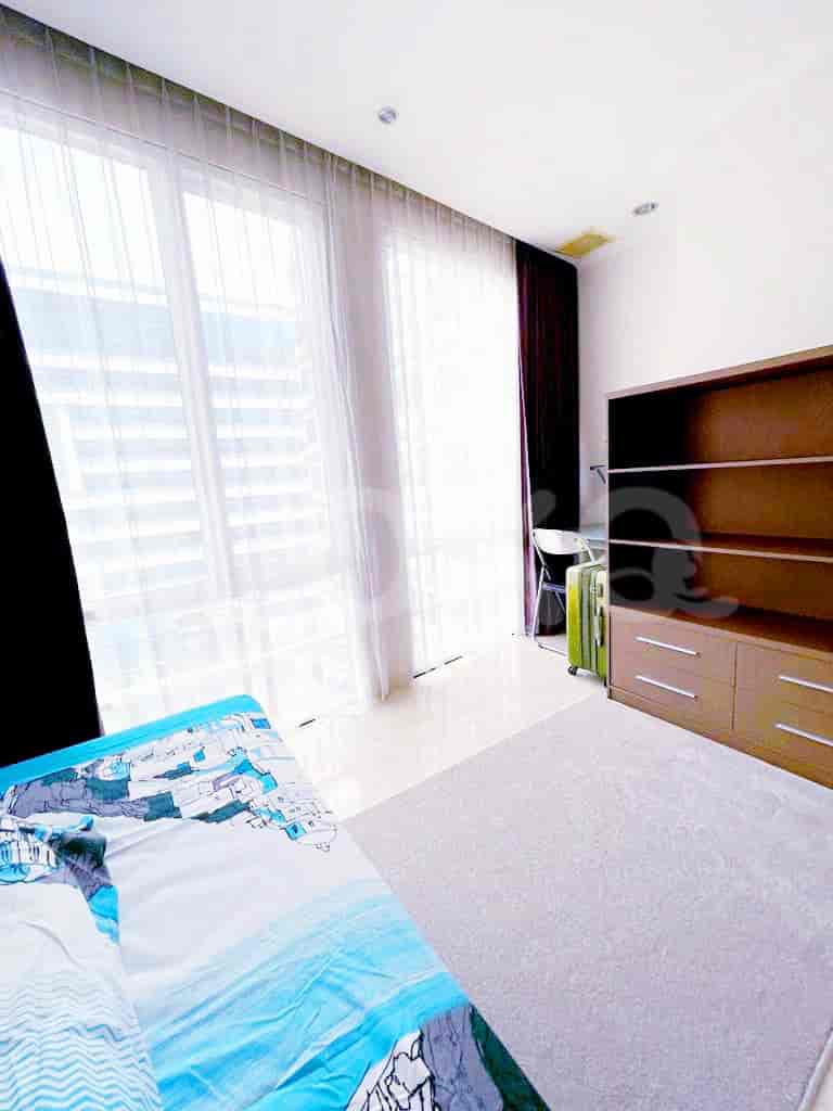 A well-lit bedroom with a large window, curtains and a study space.