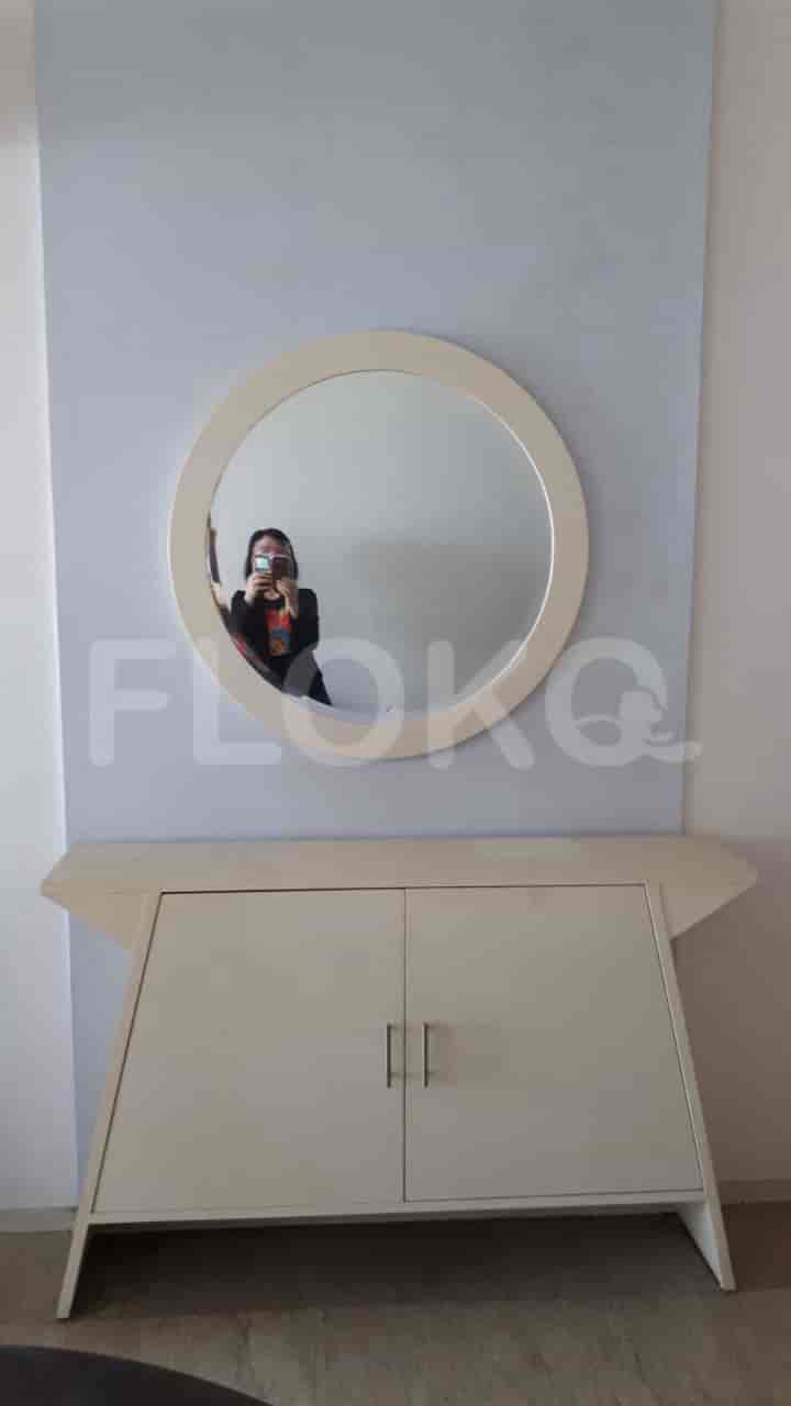 A hall with a white cabinet, mirror and wall art.