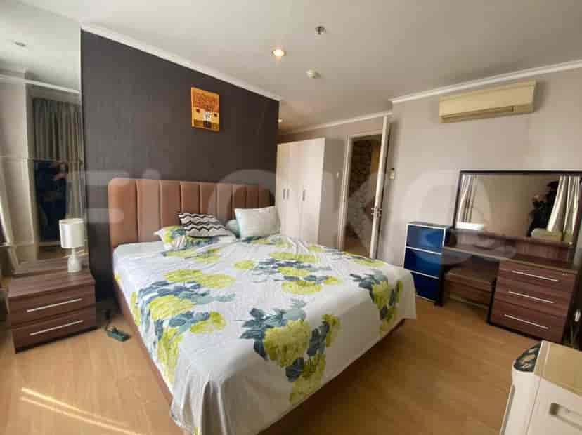 A well-lit bedroom with a large bed, side tables, and a mirror.