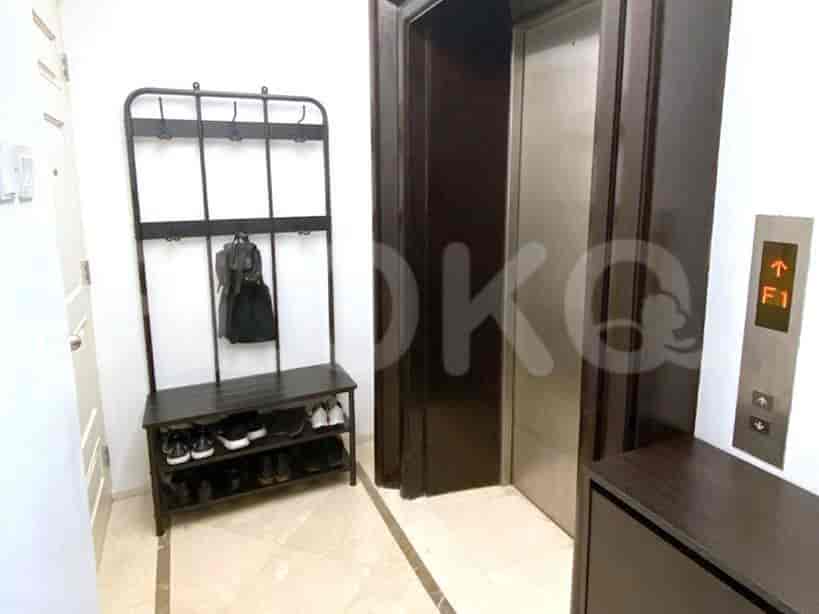 Hallway entrance with a shoe rack, elevator, and wall decor.