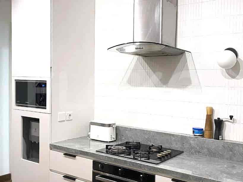 Modern kitchen with white cabinets, gray countertops, and a gas stove.