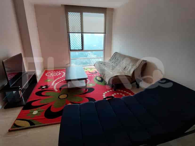 Ruang tamu yang menampilkan sofa, TV, dan karpet warna-warni.
