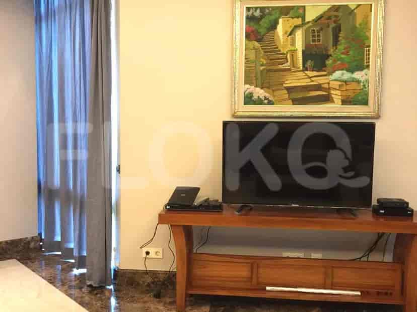 A living room setup with a TV, a wooden TV stand, and a painting.