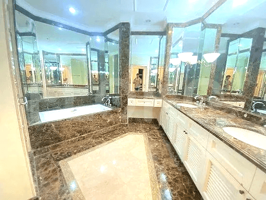 Luxurious bathroom with a bathtub, double sinks, and large mirrors.