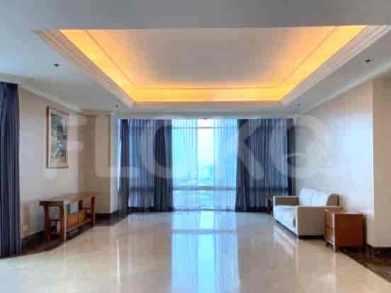 A spacious living room with a beige sofa, large windows with sheer curtains, and a marble floor.