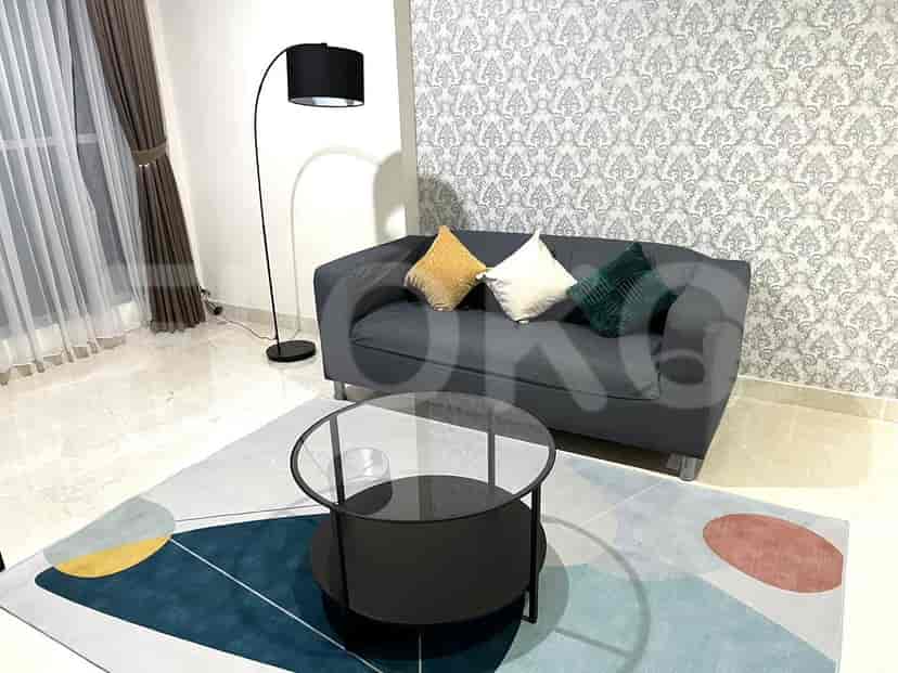 Ruang tamu modern yang menampilkan sofa abu-abu, meja kopi bundar, dan karpet bermotif.