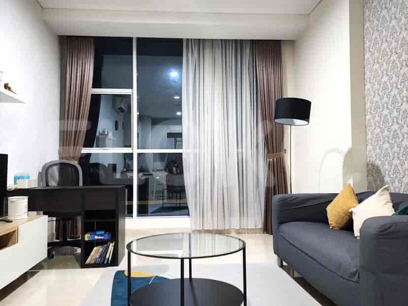 Ruang tamu dengan meja, sofa, dan jendela besar yang menghadap ke kota.