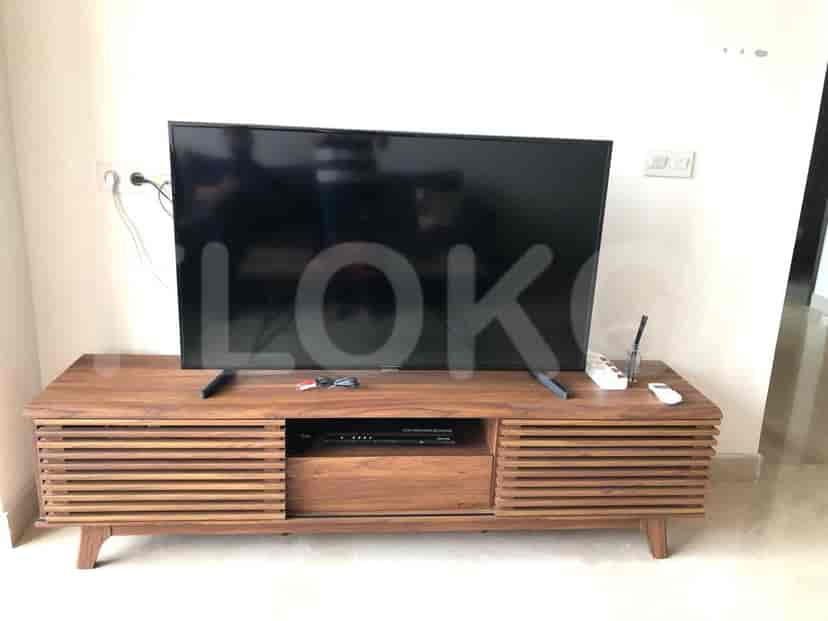 Ruang tamu dengan rak TV kayu, TV, dan kabel.