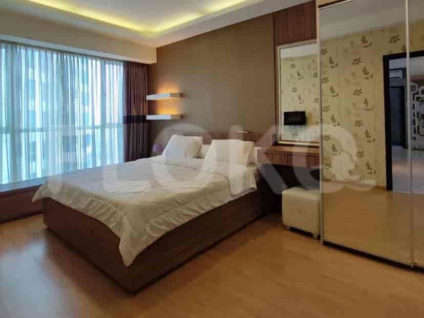 Elegant bedroom with a large bed, wooden flooring, and a full-length mirror.