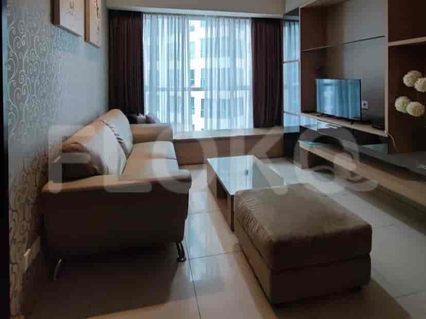 Modern living room featuring an L-shaped sofa, a glass coffee table, and a window with curtains.
