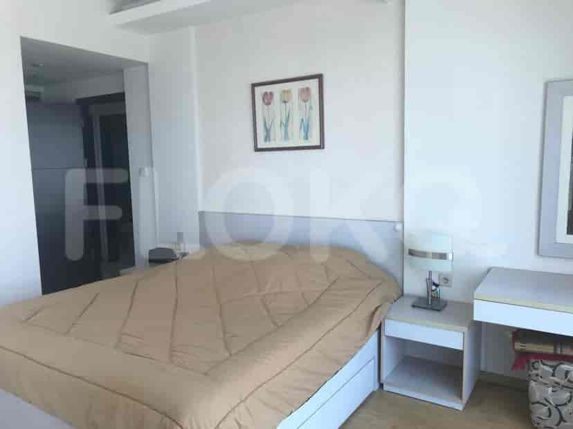 A bedroom featuring a bed with a neutral-colored duvet and a nightstand.