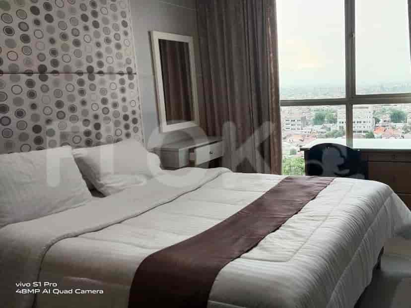 Bedroom with a bed, a vanity with a mirror, and a large window with a city view.