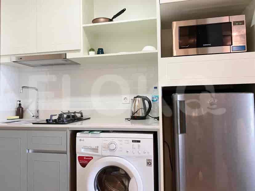 A close-up view of the kitchenette featuring a washing machine, microwave, and various kitchen tools.