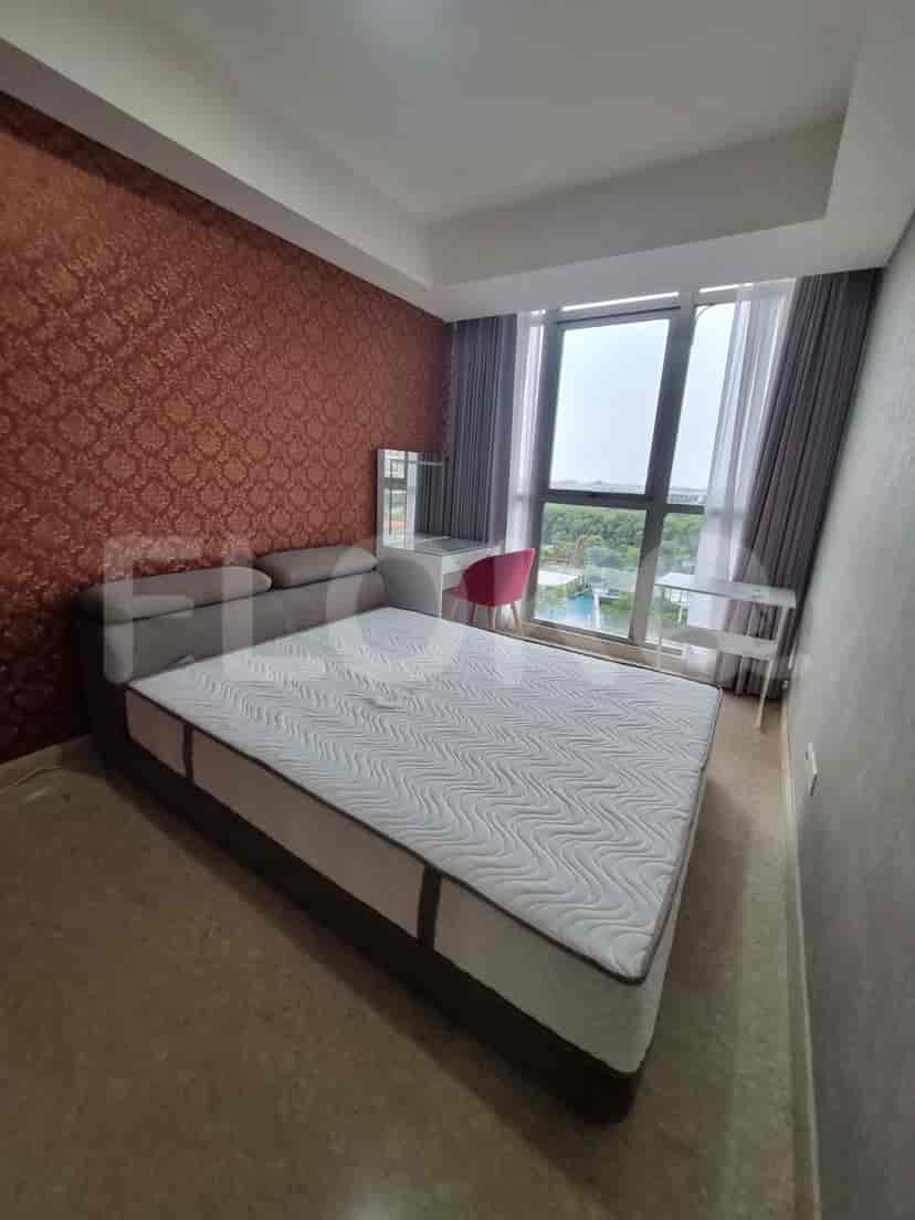 Bedroom with a queen-sized bed, dressing table with red chair, and a view of a pool.